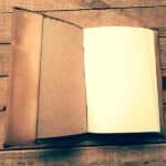 Cuaderno antiguo abierto sobre una mesa de madera envejecida